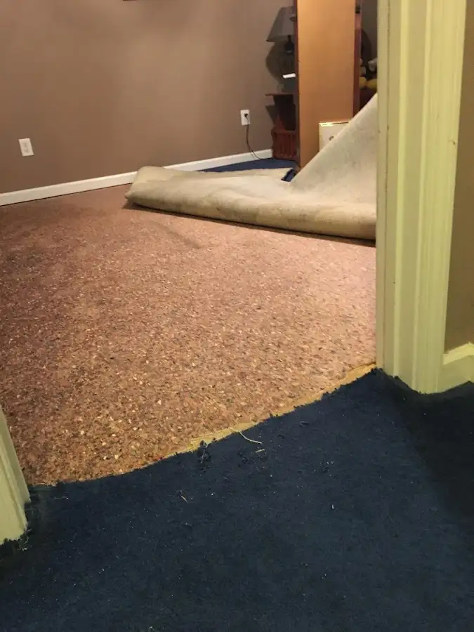 Carpet pad removal revealing water damage during Water Mitigation Services in Norman